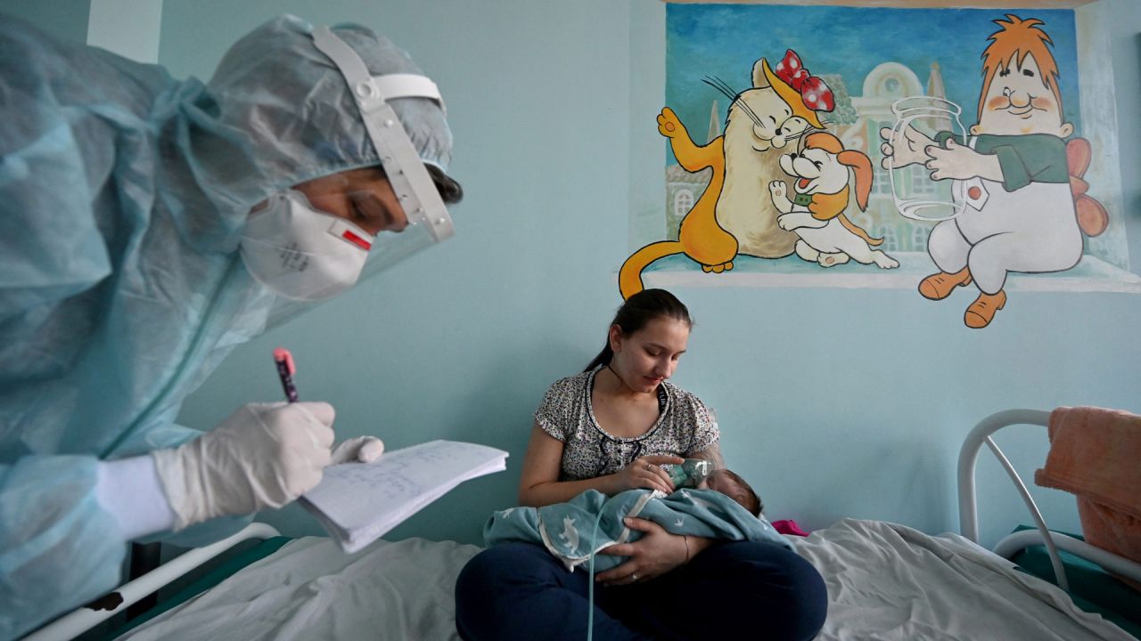 Una mujer sostiene una máscara de oxígeno sobre la cara de su bebé que sufre la enfermedad del coronavirus (Covid-19) en una sala de un hospital infantil en Kiev. | Foto:SERGEI SUPINSKY / AFP
