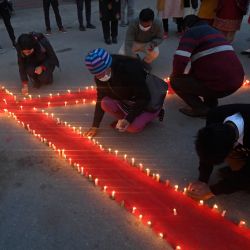 Voluntarios encienden velas formando un lazo rojo durante un acto de concienciación organizado en el Día Mundial del Sida en Katmandú. | Foto:PRAKASH MATHEMA / AFP