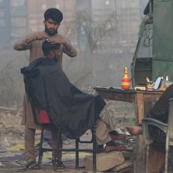 Un barbero de carretera atiende a un cliente en Lahore. | Foto:Arif ALI / AFP