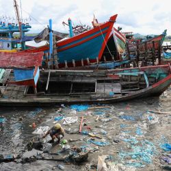 Esta foto muestra a un hombre junto a la orilla del agua, que se ve llena de barcos abandonados y residuos de plástico, en un pueblo costero de Lhokseumawe, Aceh. | Foto:AZWAR IPANK / AFP