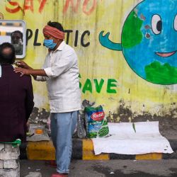 Un barbero atiende a un cliente en su puesto de carretera en Nueva Delhi. | Foto:Sajjad Hussain / AFP