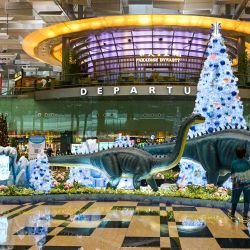 La gente toma fotos de las decoraciones navideñas en el vestíbulo de salidas del aeropuerto internacional de Changi, en Singapur. | Foto:ROSLAN RAHMAN / AFP