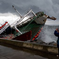 Una persona toma una foto de un barco que ha volcado debido a los fuertes vientos en Estambul. | Foto:YASIN AKGUL / AFP