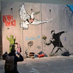 Un hombre toma una foto del mural del artista callejero británico Banksy "El Muro de Belén" durante una vista previa de la exposición "El mundo de Banksy, la experiencia inmersiva" en la estación principal de trenes Milano Centrale en Milán. | Foto:MIGUEL MEDINA / AFP