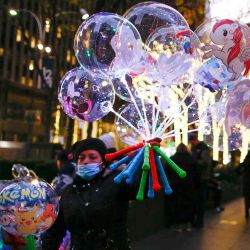 Una mujer vende globos en el centro de la ciudad de Nueva York que está nuevamente en la cima como el destino número uno para los viajeros en esta temporada navideña, la ciudad anticipa un regreso de mil millones de dólares, mientras que se espera que los viajes de vacaciones estadounidenses aumenten en más del 40%, según múltiples encuestas | Foto:AFP