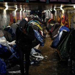 Un migrante lleva sus pertenencias en un campamento improvisado instalado debajo de un túnel peatonal que pasa por debajo de la carretera de circunvalación durante una operación de evacuación entre París y el suburbio noreste de Le Pre Saint. Christophe ARCHAMBAULT  | Foto:AFP