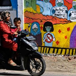 Una mujer y un niño pasan junto a un mural que promueve la concienciación sobre el coronavirus Covid-19 en Banda Aceh. CHAIDEER MAHYUDDIN  | Foto:AFP