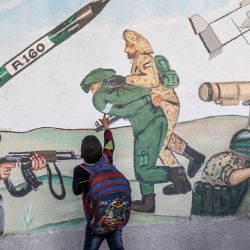 Un niño señala un mural que representa a un soldado israelí capturado mientras los palestinos conmemoran el 34º aniversario de la fundación del movimiento islamista Hamás, que gobierna la franja palestina. | Foto:SAID KHATIB / AFP