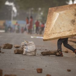 Un simpatizante del partido de la oposición bloquea una carretera mientras los agentes de policía dispersan a los simpatizantes antes de la campaña final de Harriet Nakwedde, de NUP, para las elecciones parciales a la presidencia local en Kayunga, Uganda. | Foto:BADRU KATUMBA / AFP