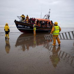 Miembros del RNLI (Royal National Lifeboat Institution) se preparan para ayudar a los migrantes a desembarcar un bote salvavidas del RNLI en una playa de Dungeness, en la costa sureste de Inglaterra. | Foto:BEN STANSALL / AFP