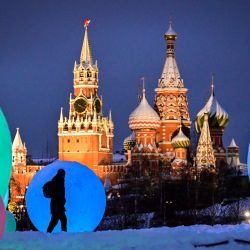Una persona pasa junto a una decoración de Navidad y Año Nuevo en el parque Zaryadie, frente a la torre Spasskaya del Kremlin y la catedral de San Basilio, en el centro de Moscú. | Foto:YURI KADOBNOV / AFP