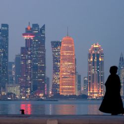 Una mujer se encuentra en el paseo marítimo con vistas a los rascacielos de la capital de Qatar, Doha. | Foto:KARIM SAHIB / AFP