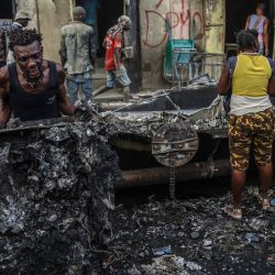 Unos hombres recogen piezas de aluminio en el lugar donde explotó un camión cisterna en Cap-Haitien, Haití. - Al menos 62 personas murieron cuando un camión cisterna de gas explotó en la ciudad haitiana de Cap-Haitien dijo un funcionario local, y los médicos abrumados dijeron que el número de víctimas iba a aumentar. | Foto:RICHARD PIERRIN / AFP