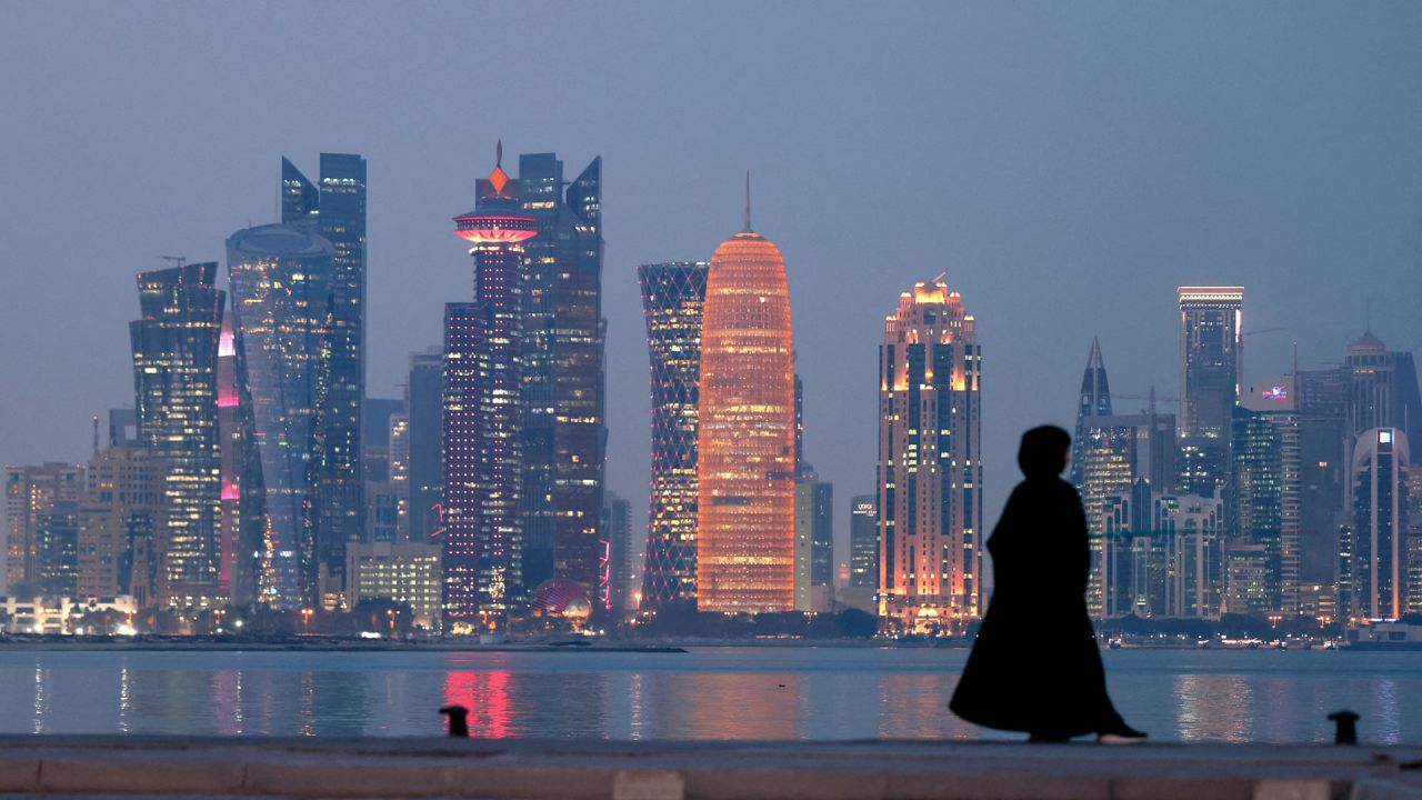 Una mujer se encuentra en el paseo marítimo con vistas a los rascacielos de la capital de Qatar, Doha. | Foto:KARIM SAHIB / AFP