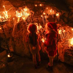 Niños vestidos con trajes de Papá Noel encienden velas durante las celebraciones del Día de Santa Bárbara, en la Iglesia Ortodoxa Griega de Santa Bárbara en el pueblo de Aboud, en la Cisjordania ocupada por Israel. | Foto:ABBAS MOMANI / AFP