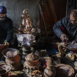 Caldereros elaboran vasijas de cobre en un taller, en la ciudad de Srinagar, capital de verano de Cachemira, administrada parcialmente por India. | Foto:Xinhua/Javed Dar
