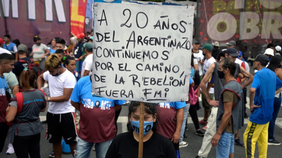 A demonstrator holds a banner reading '20 years after the Argentinazo we continue on the path of rebellion. IMF out' while marching towards Plaza de Mayo square on December 20, 2021, during the 20th anniversary of the so-called 'corralito.' 