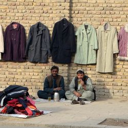 Vendedores toman un té en una acera mientras esperan a los clientes en Kandahar, Afganistan. | Foto:JAVED TANVEER / AFP