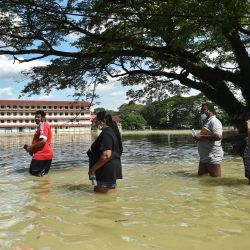 La gente camina a través de las aguas de la inundación en Shah Alam, Selangor, mientras Malasia se enfrenta a las inundaciones masivas que han dejado al menos 14 muertos y más de 70.000 desplazados. | Foto:ARIF KARTONO / AFP