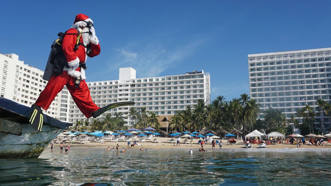 Un hombre disfrazado de Papá Noel salta al agua en la playa de Acapulco, estado de Guerrero, México. | Foto:FRANCISCO ROBLES / AFP