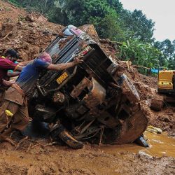 Los trabajadores de rescate empujan un vehículo volcado atascado en el barro y los escombros en el lugar de un deslizamiento de tierra que fue causado por las fuertes lluvias en Kokkayar, India. | Foto:AFP