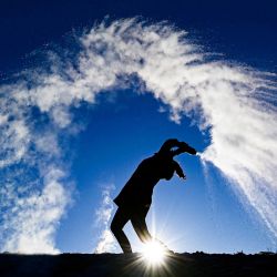 Una mujer lanza agua caliente de una botella al aire frío haciendo visibles sus tres fases -líquido, gas, sólido- mientras las gotas más pequeñas se enfrían y evaporan en una dramática nube antes de llegar al suelo como nieve, en Berlín en un soleado pero gélido Día de San Esteban. | Foto:Tobias Schwarz / AFP