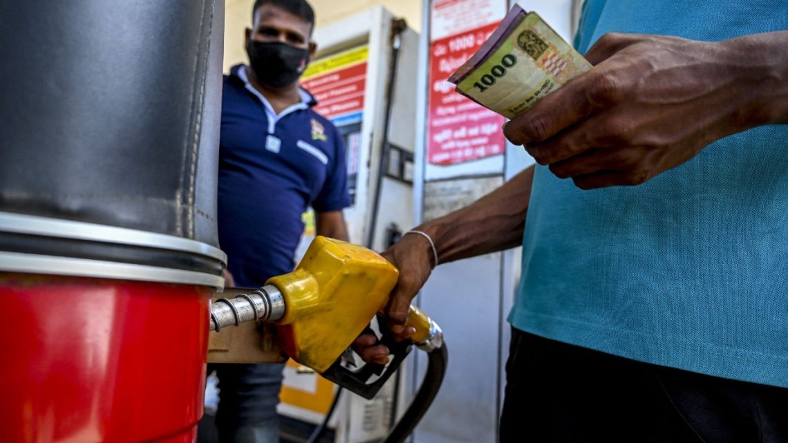 A worker fills the tank of an auto rickshaw with petrol at a petrol station in Embilipitiya on December 21, 2021.