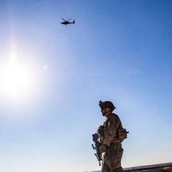 Un helicóptero de ataque estadounidense AH-64 Apache vuela por encima de los soldados estadounidenses que patrullan a lo largo de las líneas de frente entre las áreas en poder de las Fuerzas Democráticas Sirias (SDF) y los combatientes respaldados por Turquía cerca de la aldea de Dardara en el campo de Tal Tamr en la provincia nororiental de Hasakeh. | Foto:Delil souleiman / AFP
