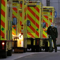 Un miembro de la tripulación de una ambulancia es visto junto a las ambulancias estacionadas fuera del hospital Royal London en Londres. - Inglaterra ha seguido adelante con su campaña de vacunación contra el virus Covid-19 en la carrera por inocular al mayor número posible de personas mientras el número de casos de la variante del coronavirus Omicron se dispara. | Foto:Hollie Adams / AFP