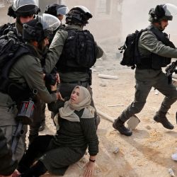 Los palestinos son bloqueados por las fuerzas de seguridad israelíes mientras intentan detener la demolición de su casa, situada dentro del "Área C" de la Cisjordania ocupada, donde Israel mantiene el control total sobre la planificación y la construcción. | Foto:HAZEM BADER / AFP