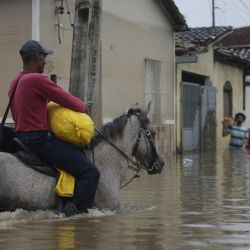Un hombre monta un caballo mientras cruza por una calle inundada provocada por las fuertes lluvias, en Dário Meira, estado de Bahía, Brasil. | Foto:Xinhua/Lucio Tavora