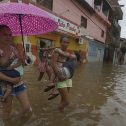Mujeres caminan por una calle inundada provocada por las fuertes lluvias, en Dário Meira, estado de Bahía, Brasil. | Foto:Xinhua/Lucio Tavora