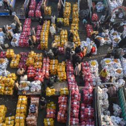 Vendedores de fruta al por mayor tratan con los clientes y sus proveedores en un mercado de frutas en Lahore. | Foto:ARIF ALI / AFP