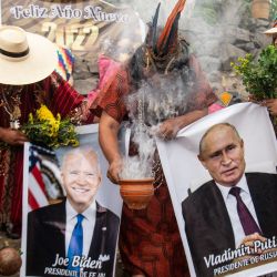 Los chamanes que realizan un ritual de predicciones para el próximo año muestran carteles del presidente ruso Vladimir Putin y del presidente estadounidense Joe Biden en el cerro San Cristóbal en Lima. | Foto:ERNESTO BENAVIDES / AFP