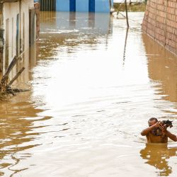 Un hombre carga a un perro para cruzar una calle inundada, en Itapetinga, estado de Bahía, Brasil. El río Catolé se desbordó a causa de la lluvia provocando inundaciones en varios puntos de la ciudad de Itapetinga. | Foto:Xinhua/Manuella Luana