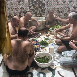 Unos hombres almuerzan después de bañarse en Hammam al-Qawas, una casa de baños tradicional turca, en la ciudad septentrional de Siria, Alepo. | Foto:AFP