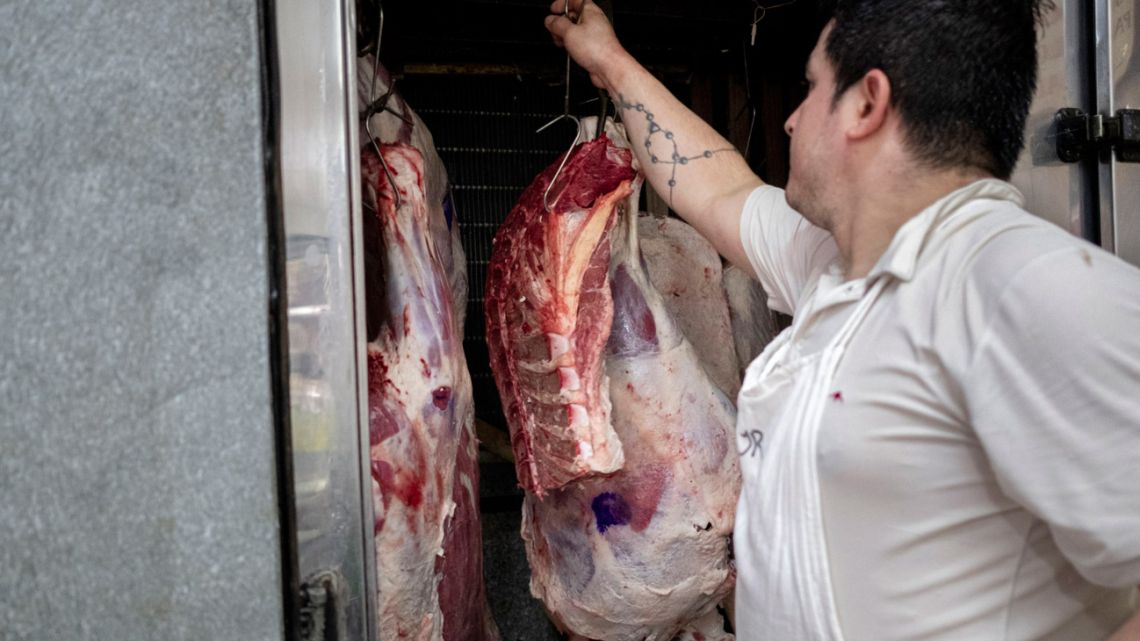 A butcher takes delivery of a beef carcass outside a butcher's shop in Buenos Aires.