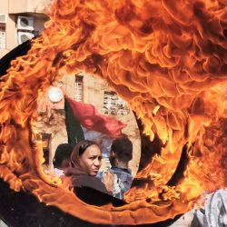 Un manifestante observa desde detrás de un neumático en llamas una barricada improvisada erigida durante una protesta para exigir un gobierno civil en la "Calle 40" de la ciudad gemela de Omdurman, la capital sudanesa.  | Foto:AFP