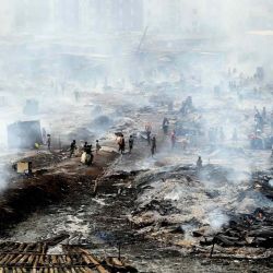 Trabajadores y residentes locales intentan rescatar mercancías del incendio en el mayor mercado de madera de Lagos, el aserradero de Oko-Baba, en Ebute-Metta, de Nigeria. | Foto:AFP