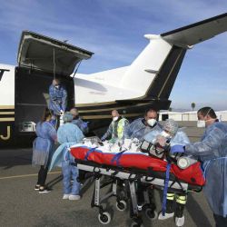 Los paramédicos, enfermeras y médicos utilizan un carro para transferir a un paciente afectado por el coronavirus (Covid-19) de una ambulancia a un avión médico en Bastia en la isla mediterránea francesa de Córcega. Pascal | Foto:AFP