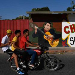 Una motocicleta pasa frente a un mural que representa al fallecido presidente venezolano Hugo Chávez en Sabaneta -ciudad natal del candidato del partido de gobierno de Venezuela a gobernador del estado, Jorge Arreaza.  | Foto:AFP