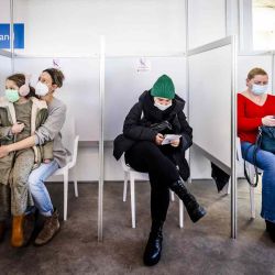 Los miembros del público se sientan en una sala de espera en caso de una reacción inmediata después de recibir inyecciones de refuerzo en un centro de vacunación Covid-19 establecido en SchipholSirport en Amsterdam. | Foto:AFP