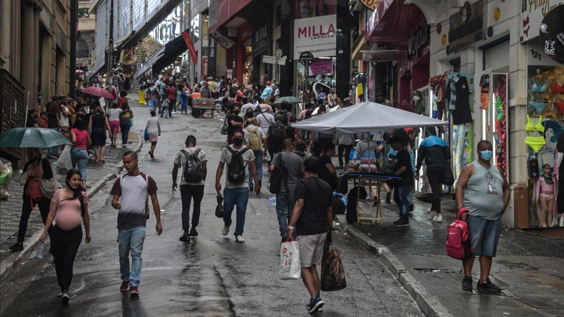 People walk along a commercial street in downtown São Paulo, Brazil, on December 30, 2021. 
