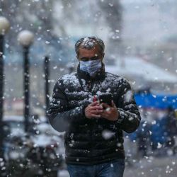 Un hombre revisa su teléfono móvil mientras camina por una calle durante una nevada en Srinagar. TAUSEEF MUSTAFA / AFP | Foto:AFP