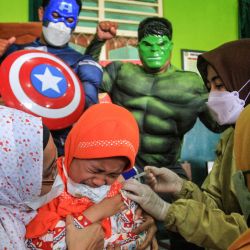 Personal médico vestido con trajes de superhéroes del Capitán América y Hulk acompañan a niños de 6 a 11 años mientras reciben la vacuna contra el coronavirus Sinovac COVID-19 en una escuela de Yogyakarta, Indonesia. | Foto:Devi Rahman / AFP