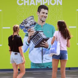 La gente mira una imagen del serbio Novak Djokovic antes del Abierto de Australia en el centro de tenis Melbourne Park en Melbourne. | Foto:William West / AFP