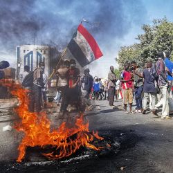 Manifestantes sudaneses caminan junto a neumáticos en llamas mientras se concentran para protestar contra el golpe militar de octubre de 2021, en la capital, Jartum. | Foto:AFP
