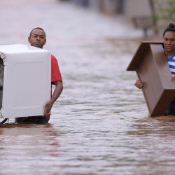 Personas vadean el agua mientras sacan sus pertenencias de sus casas en el inundado municipio brasileño de Juatuba, situado en el estado de Minas Gerais, después de las lluvias extremadamente fuertes que han caído en los últimos días en el sureste del país. | Foto:DOUGLAS MAGNO / AFP