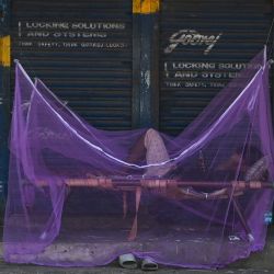 Un hombre duerme una siesta dentro de un mosquitero junto a las tiendas cerradas en una zona de mercado durante el cierre impuesto por el gobierno estatal como medida preventiva contra la propagación del coronavirus Covid-19 en Chennai, India. | Foto:ARUN SANKAR / AFP