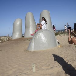 Una mujer se toma una fotografía sobre la escultura "Los Dedos" en la playa Brava, en Punta del Este, en el departamento de Maldonado, Uruguay. | Foto:Xinhua/Nicolás Celaya
